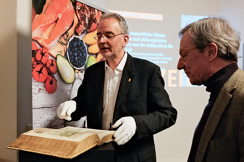 Bild, auf dem zu sehen ist, wie IAG-Sprecher Ralph Bock Einblick in das Kräuterbuch-Original aus dem 16. Jahrhundert gewährt